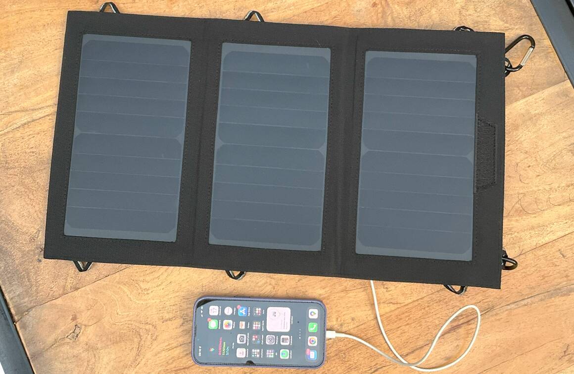 Chargeur solaire pliable posé face au soleil avec un smartphone en cours de recharge